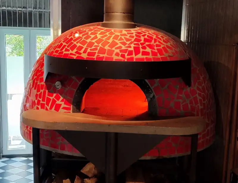 Czerwony piec do pizzy nad stosem drewna
