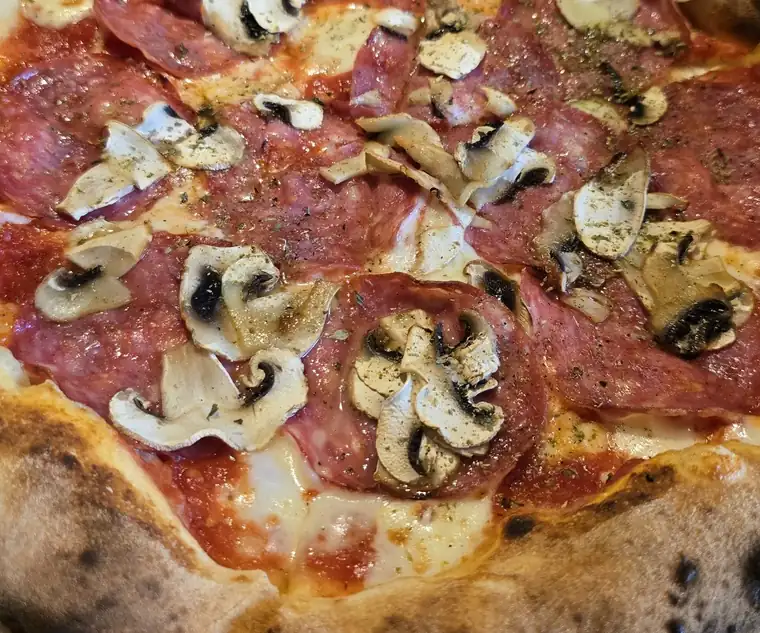 Pizza z szynką i pieczarkami na drewnianej desce
